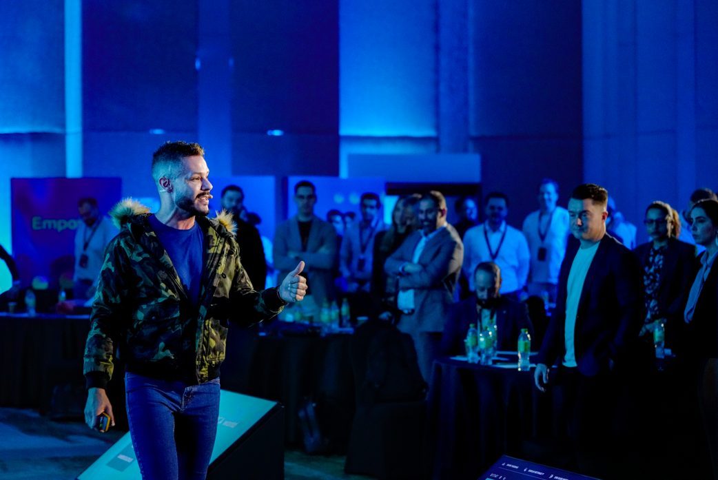 Andrew Wolhuter on stage under blue light with the audience standing